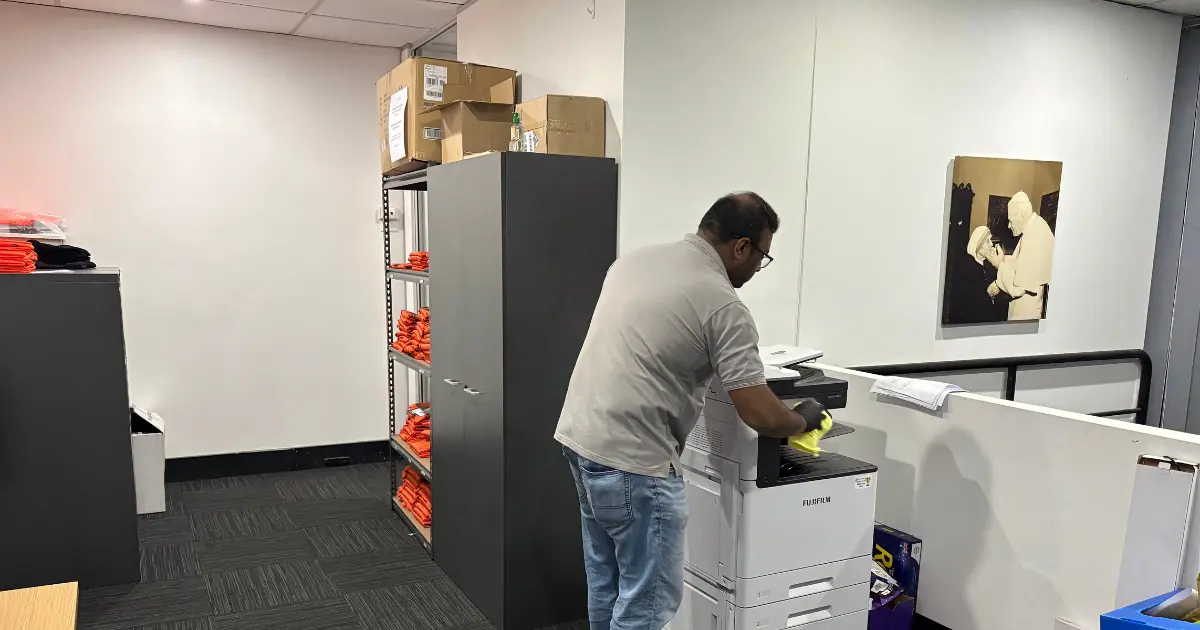 Cleaner wiping a printer and work area in a Western Sydney office