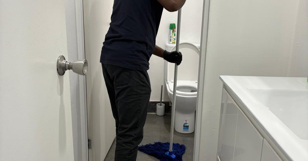 Professional office cleaner disinfecting a commercial bathroom during routine office cleaning.