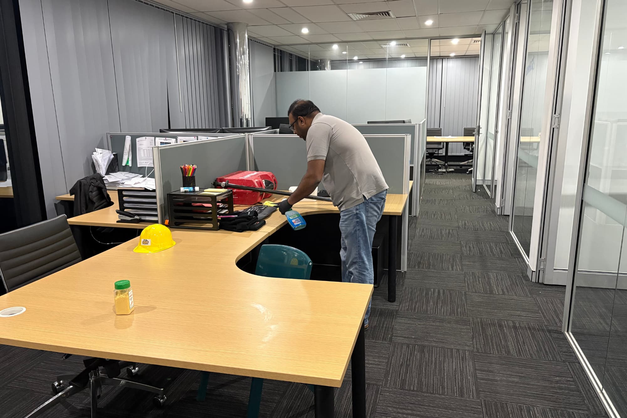 Cleaner wiping desks and surfaces in a commercial office