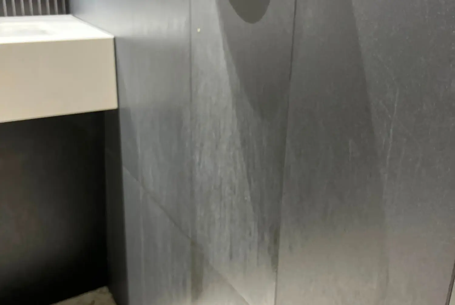Commercial washroom tiled wall before cleaning, with visible marks