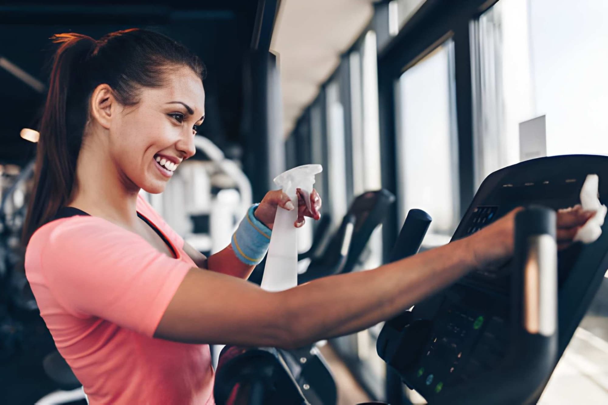 Cleaner wiping gym equipment with disinfectant
