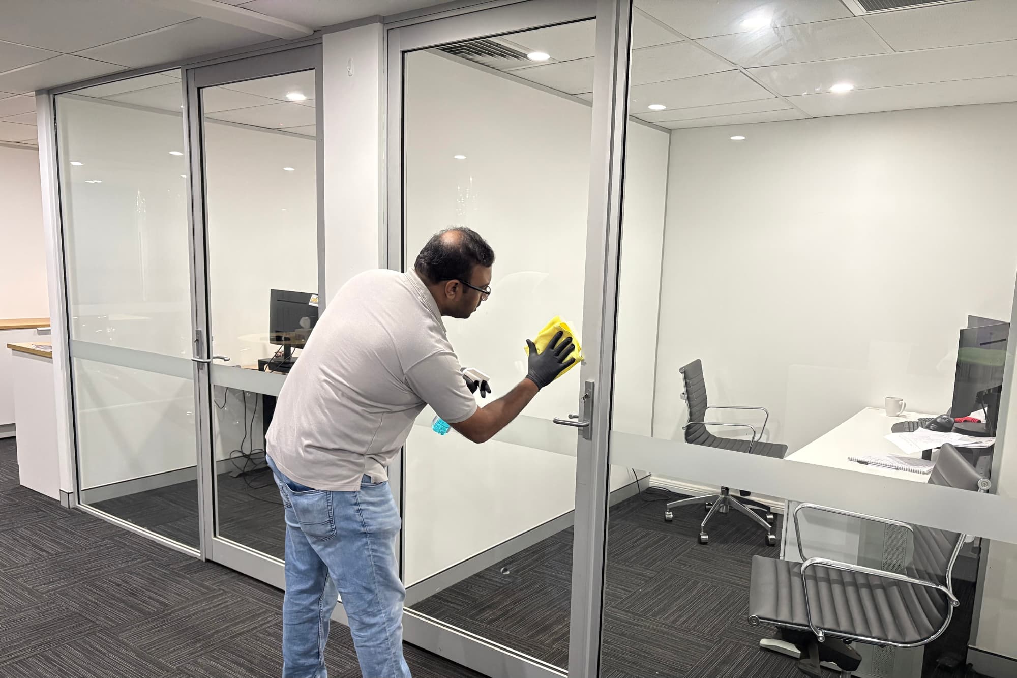 Cleaner wiping glass office windows